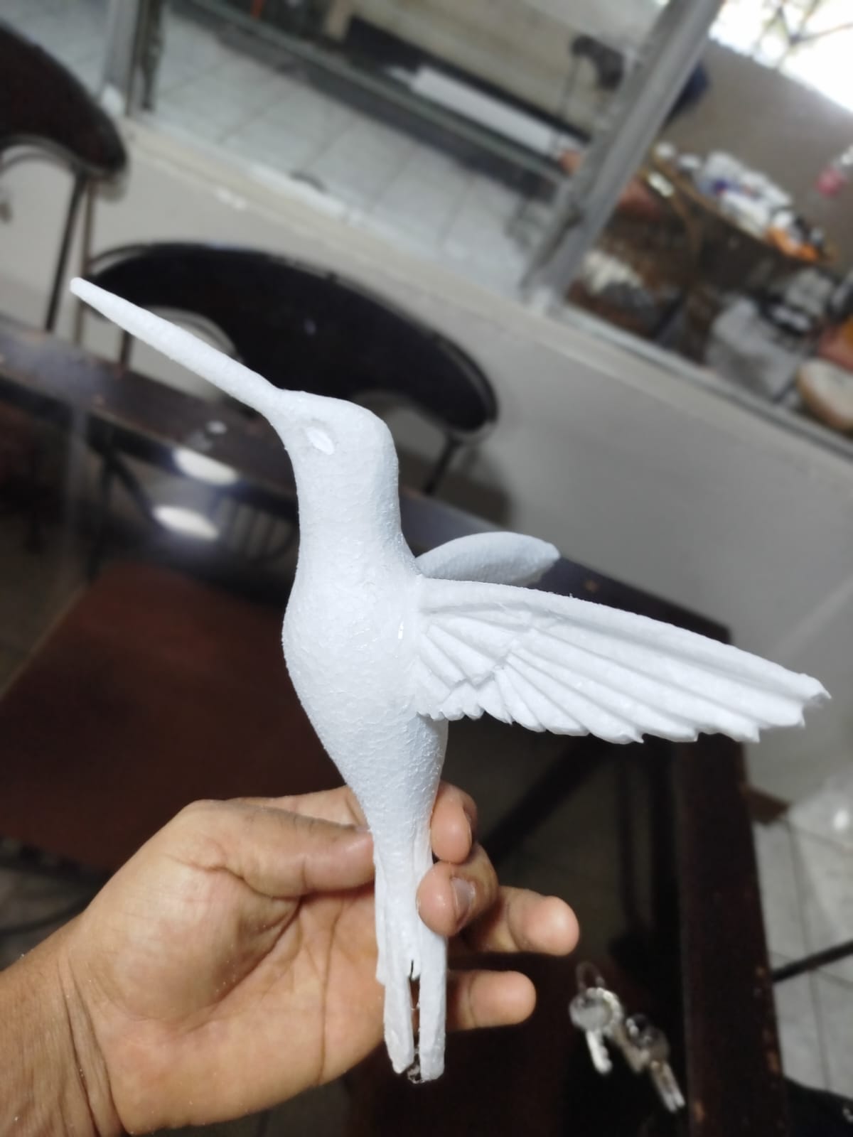 Figura de colibrí hecha de espuma blanca sostenida en la mano